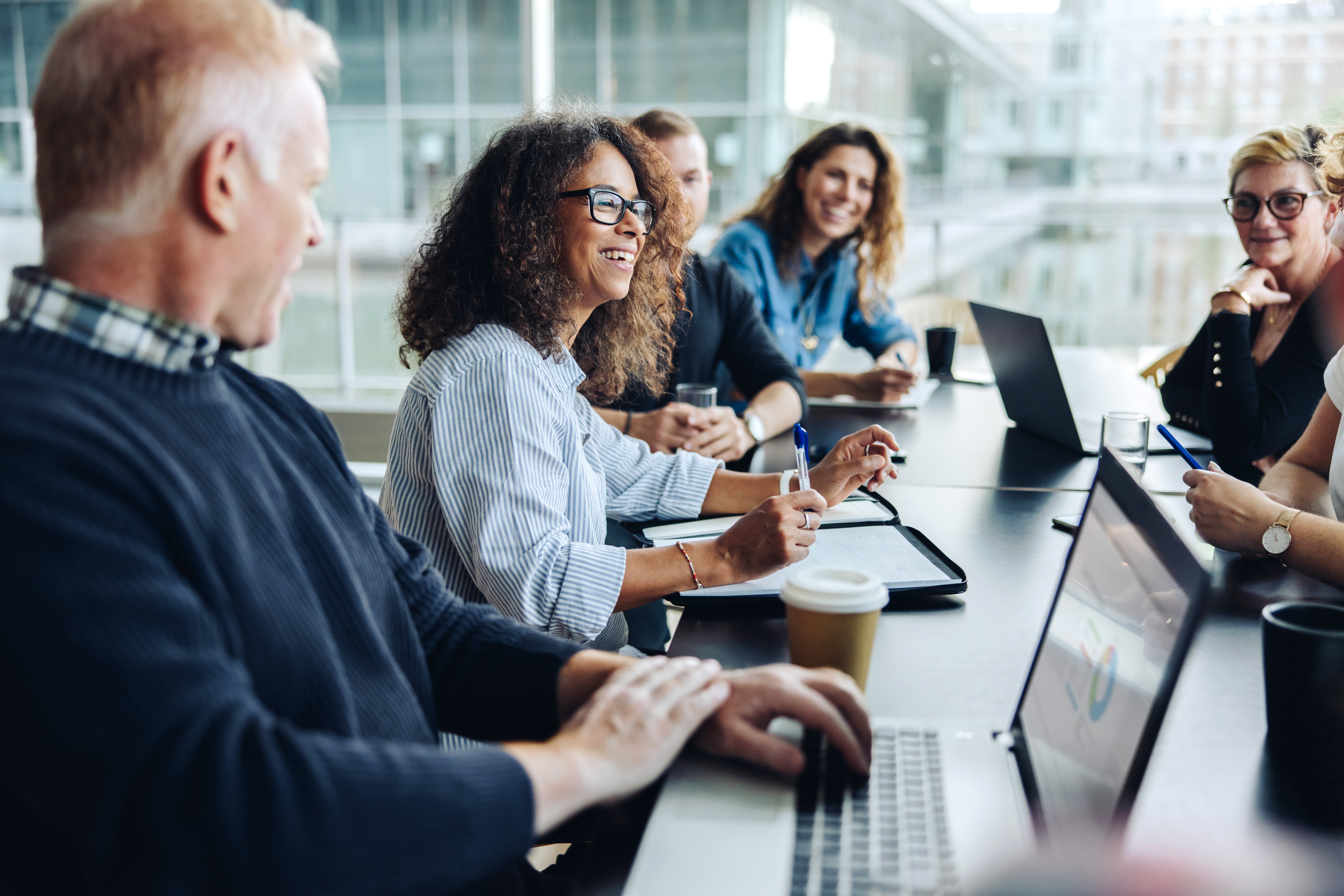 Multi-ethnic business people smiling during a meeting in conference room. Team of professionals having meeting in boardroom.